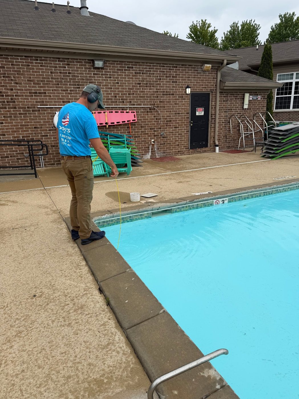 Technician performing pool leak detection at the pool edge with specialized equipment