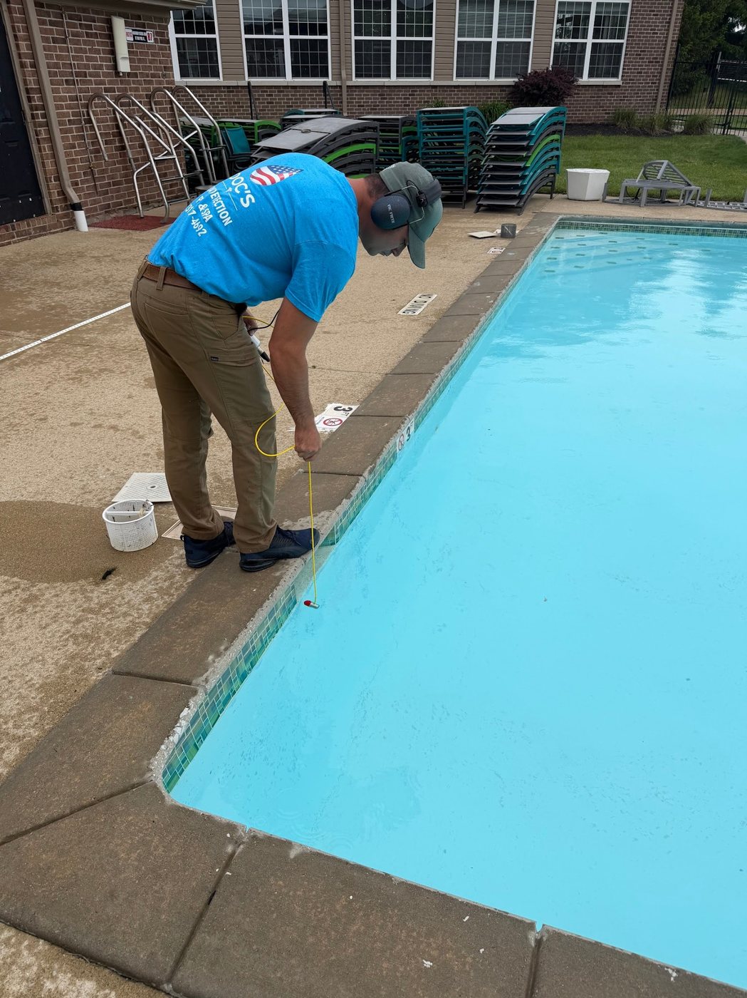 Technician performing detailed pool leak detection checks near the wall and light area